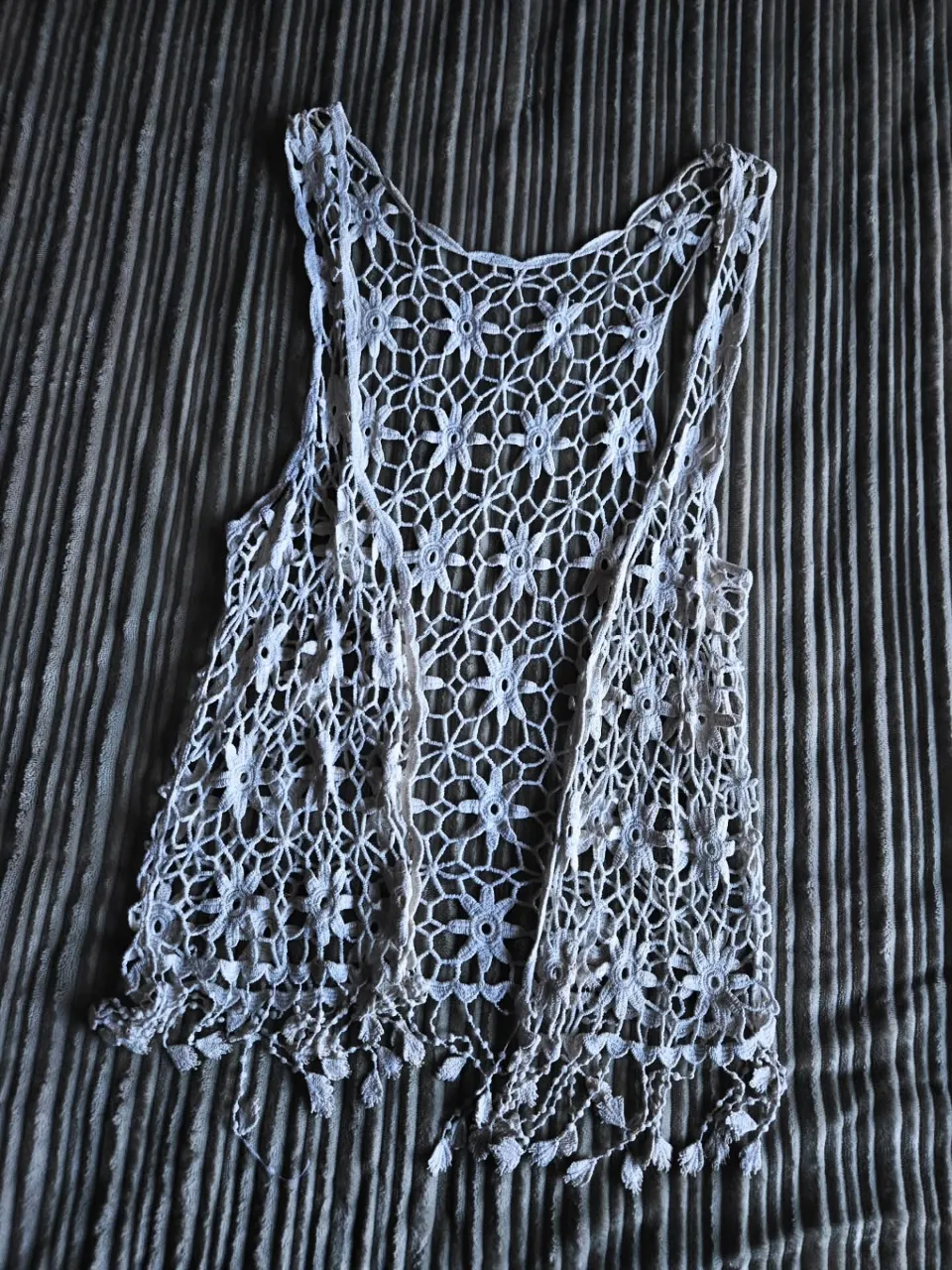 Chaleco tejido al crochet en color blanco. Posee detalles de flores caladas y flecos en la parte inferior.