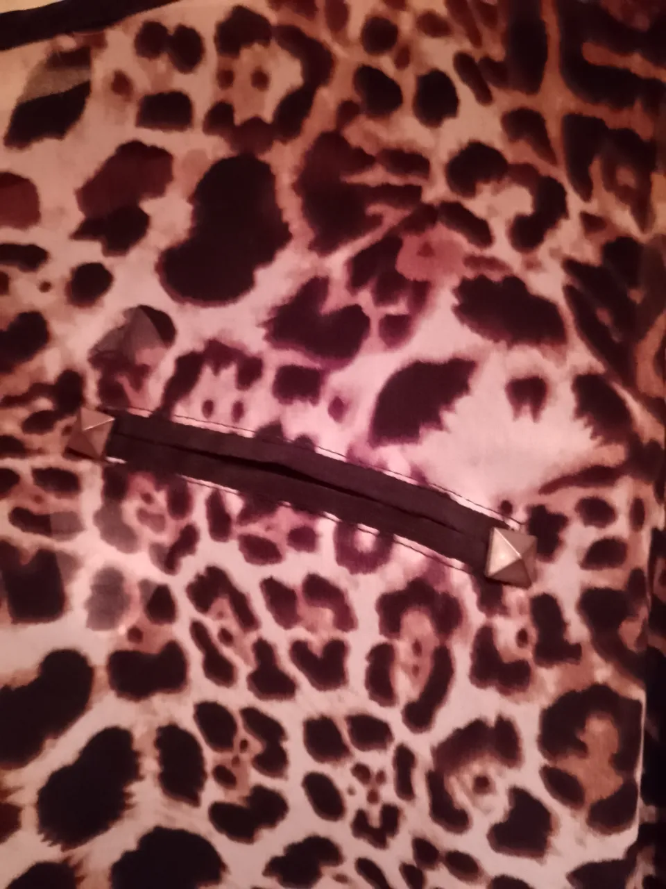 Blusa estampada con motivo de leopardo, manga larga y detalle de lazo en la espalda. Posee un bolsillo en el frente con tachas metálicas.Le falta un botón de la manga