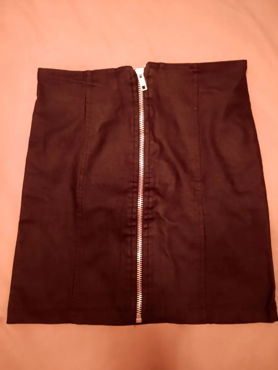 Pollera negra tiro alto con cierre metálico al frente. Diseño moderno y versátil, ideal para looks cancheros.