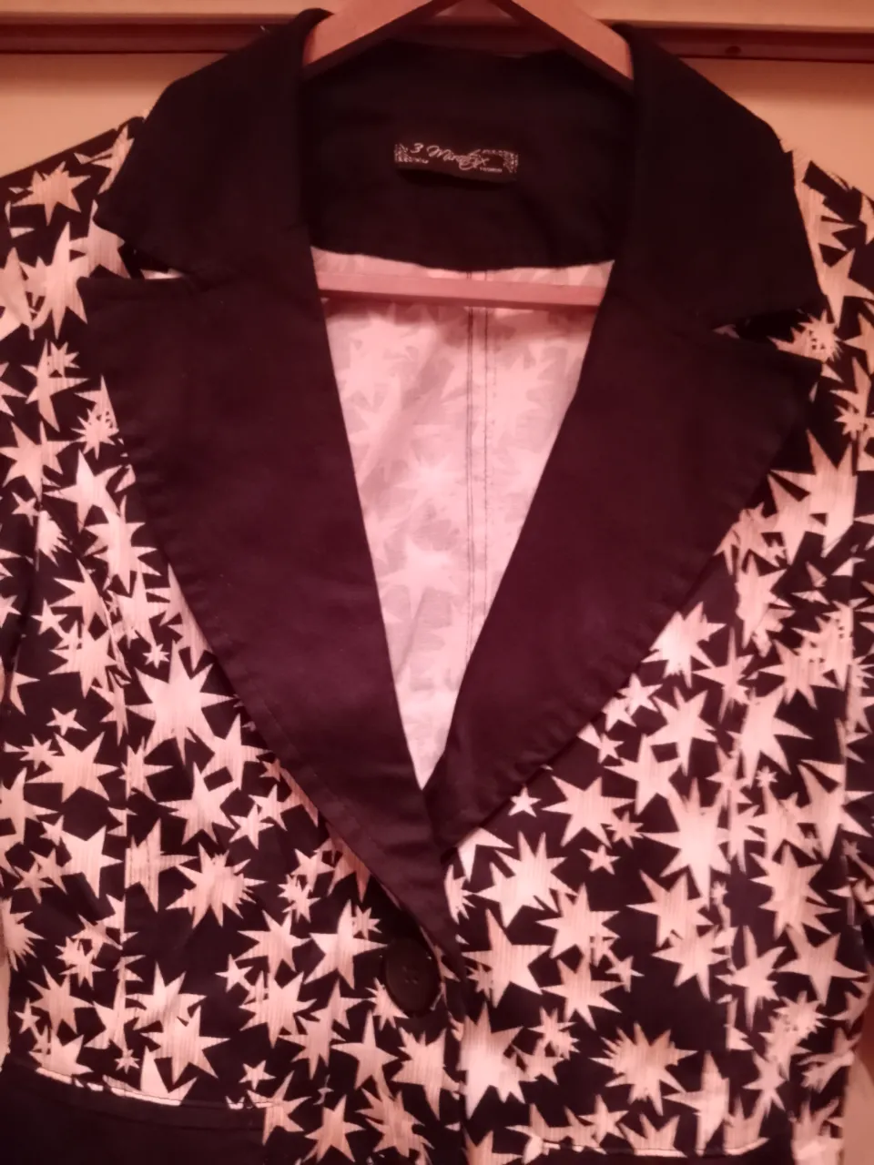 Blazer estampado con estrellas blancas sobre fondo negro. Posee solapa y dos botones al frente. Ideal para un look canchero y original.