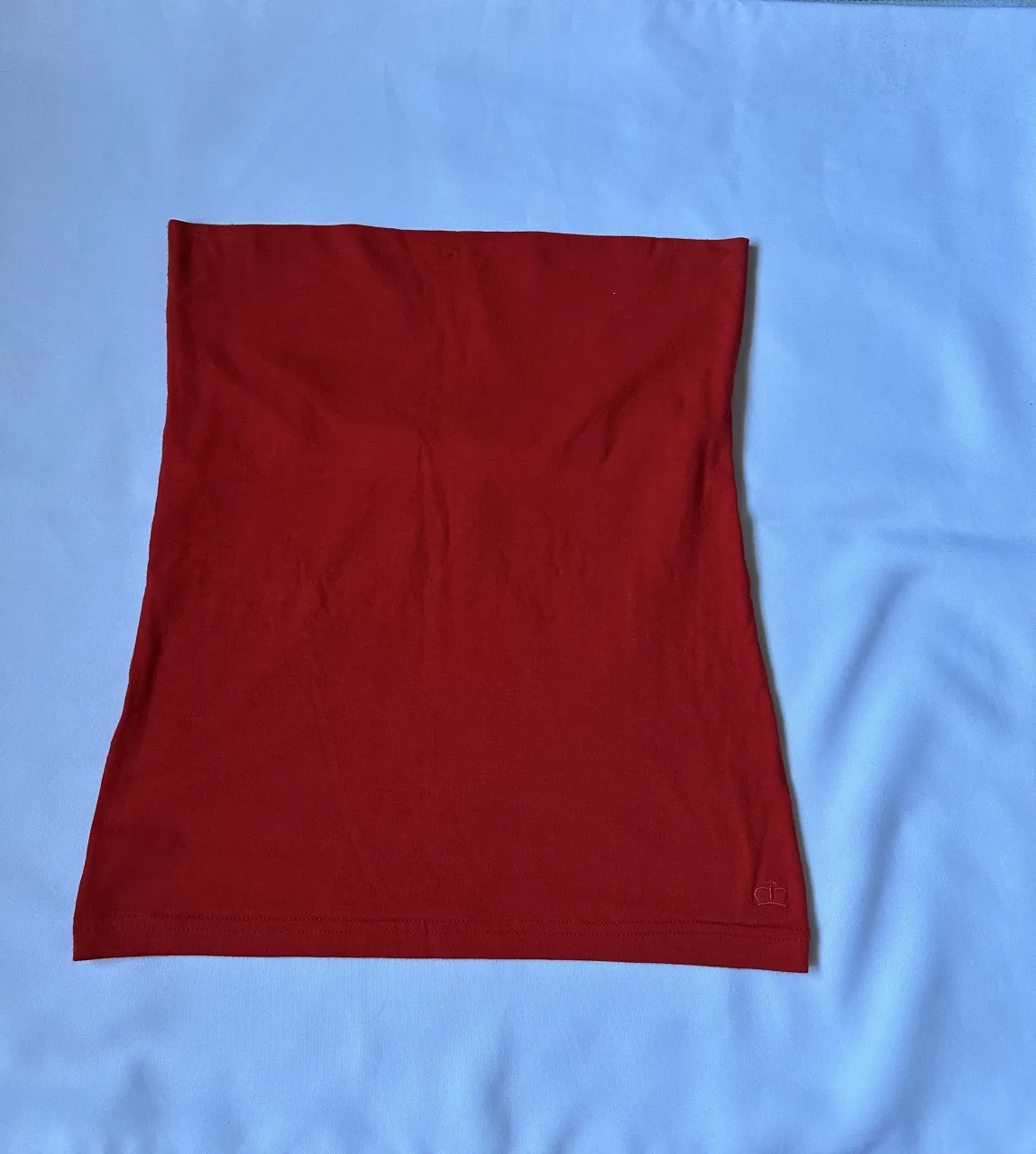 Top strapless de color rojo. Posee un detalle de logo en la parte inferior derecha.