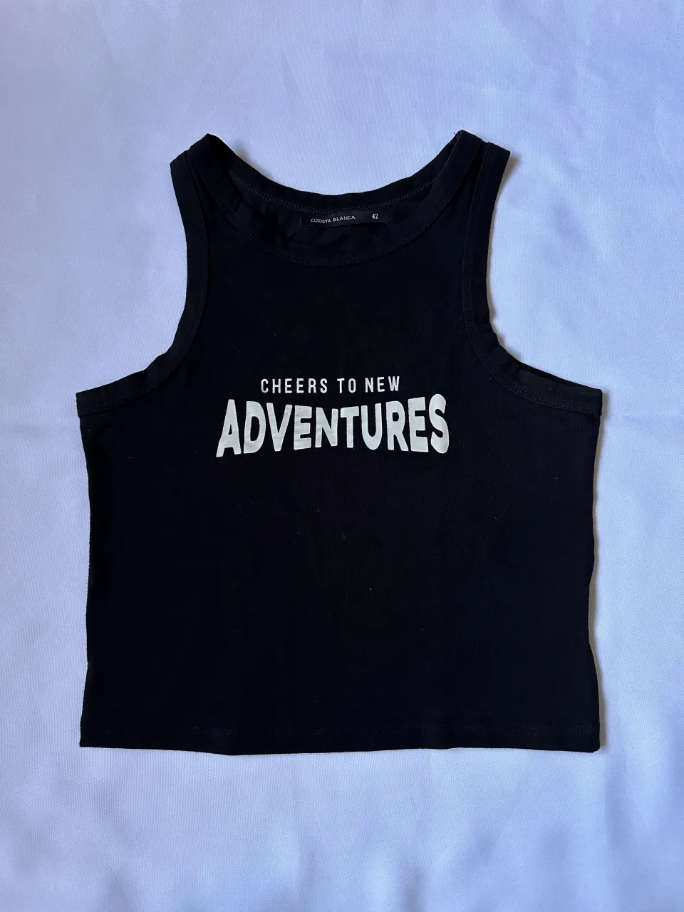 Musculosa negra con estampa "CHEERS TO NEW ADVENTURES" en blanco.