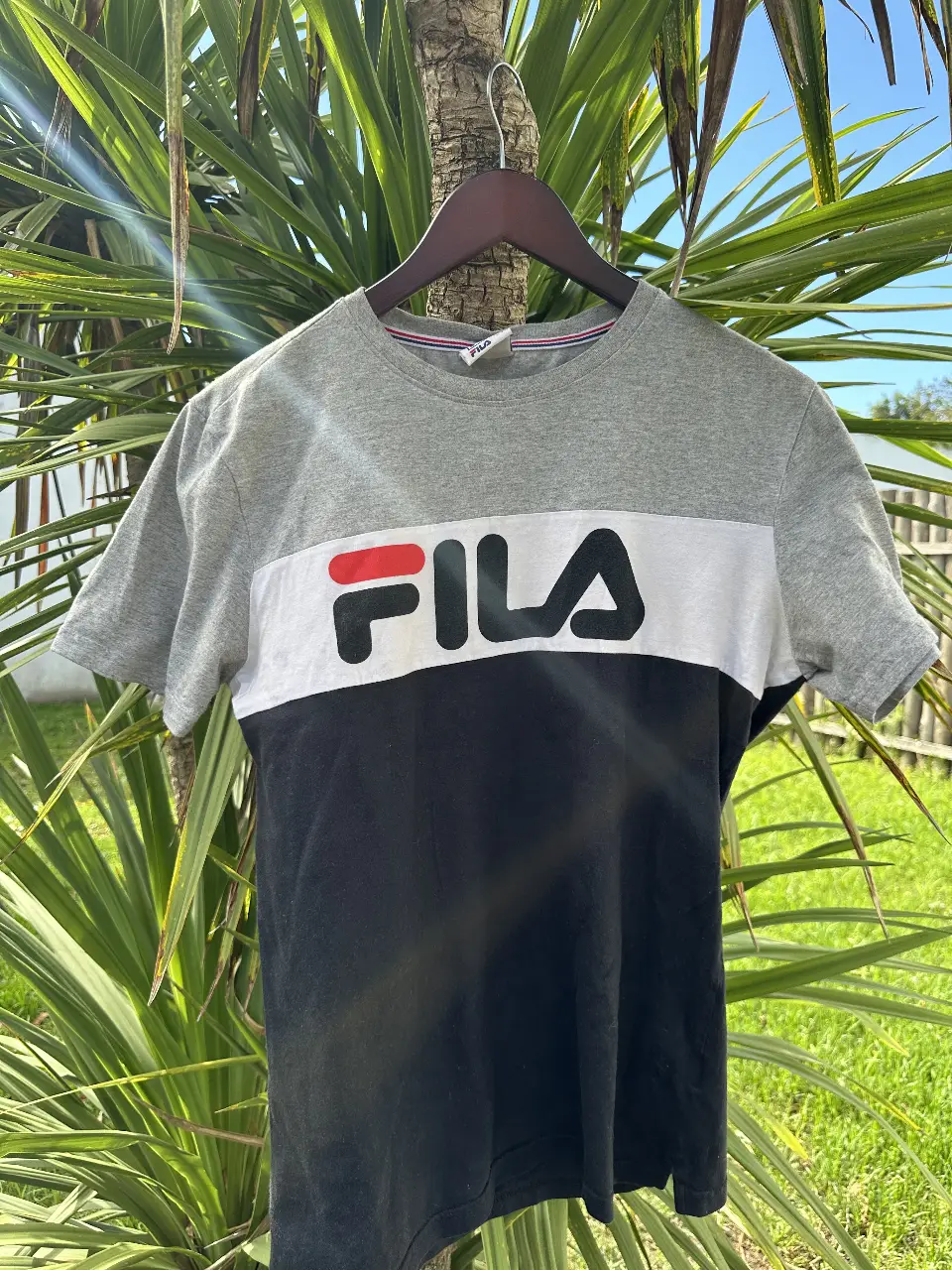 Remera deportiva Fila para hombre, de manga corta y cuello redondo. Diseño bicolor en gris y negro con el logo de la marca en el frente.