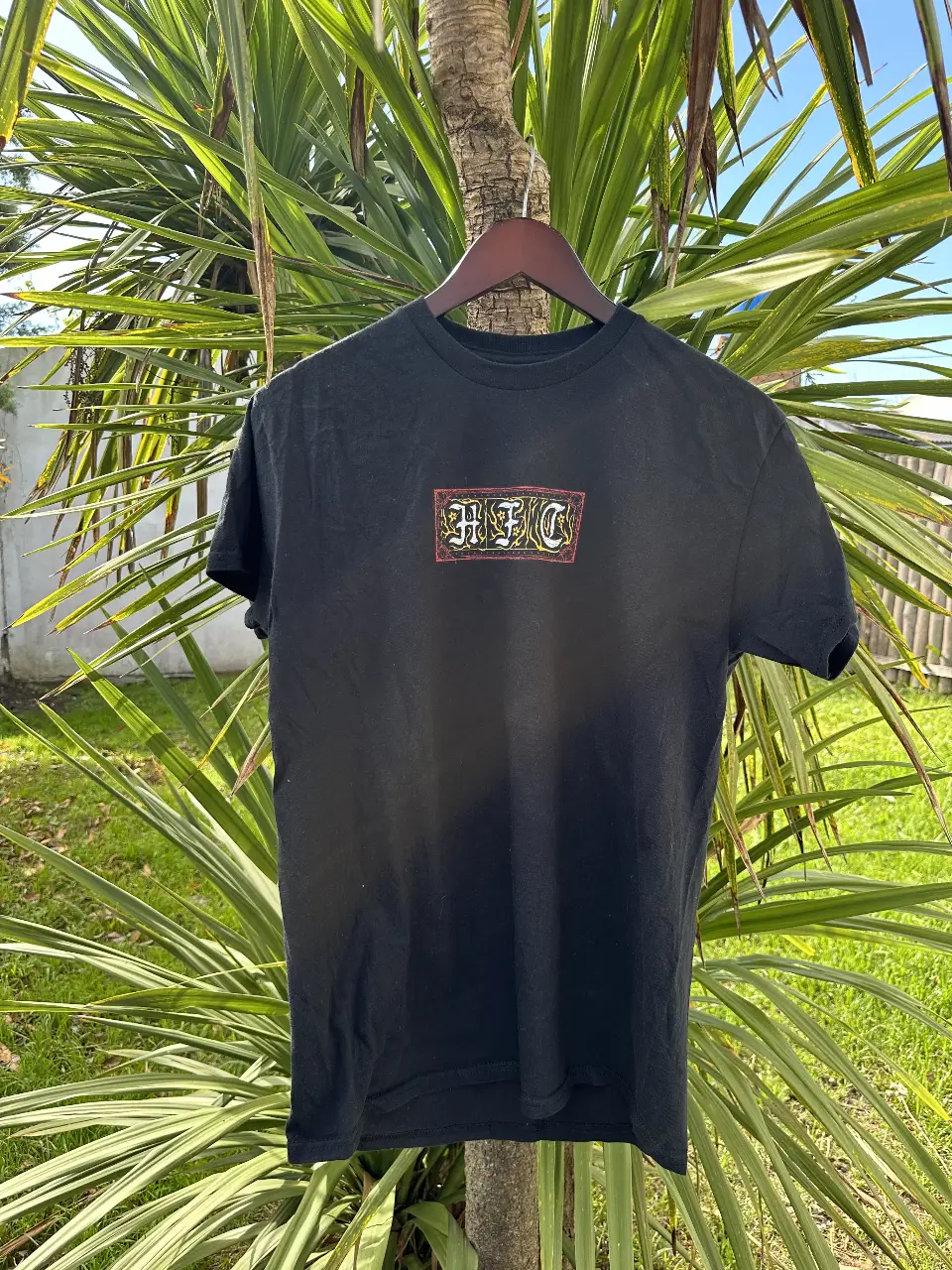 Remera negra de Stranger Things con estampado en la espalda del Demogorgon y el logo de la serie. En el frente, un logo con las siglas "HFC". Talle M.
