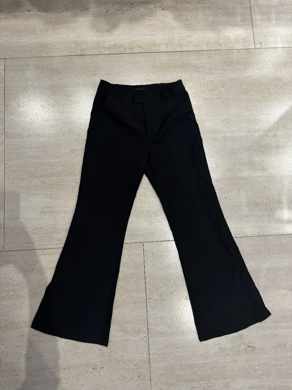 Pantalón sastrero negro con corte campana, ideal para un look elegante y moderno. Perfecto para combinar con blusas o camisas.