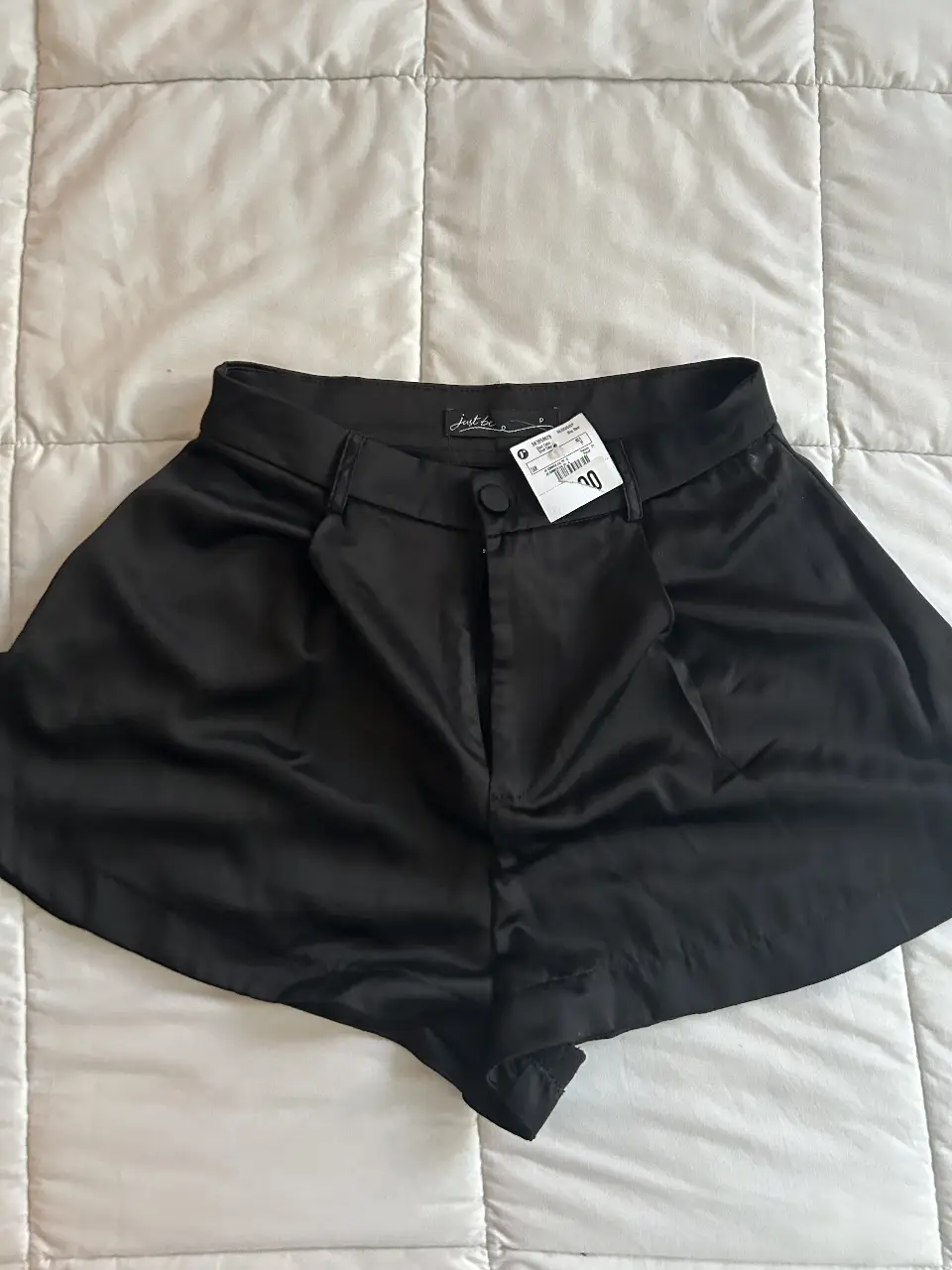 Short negro de satén, tiro alto, con pinzas y botón. Ideal para un look elegante y moderno.