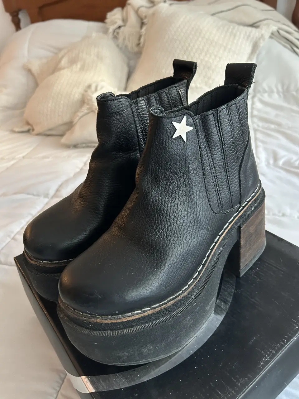 Botines negros de cuero con plataforma y taco de madera. Diseño con estrella en el lateral y elásticos en los costados para un calce fácil. Ideales para un look moderno y canchero.