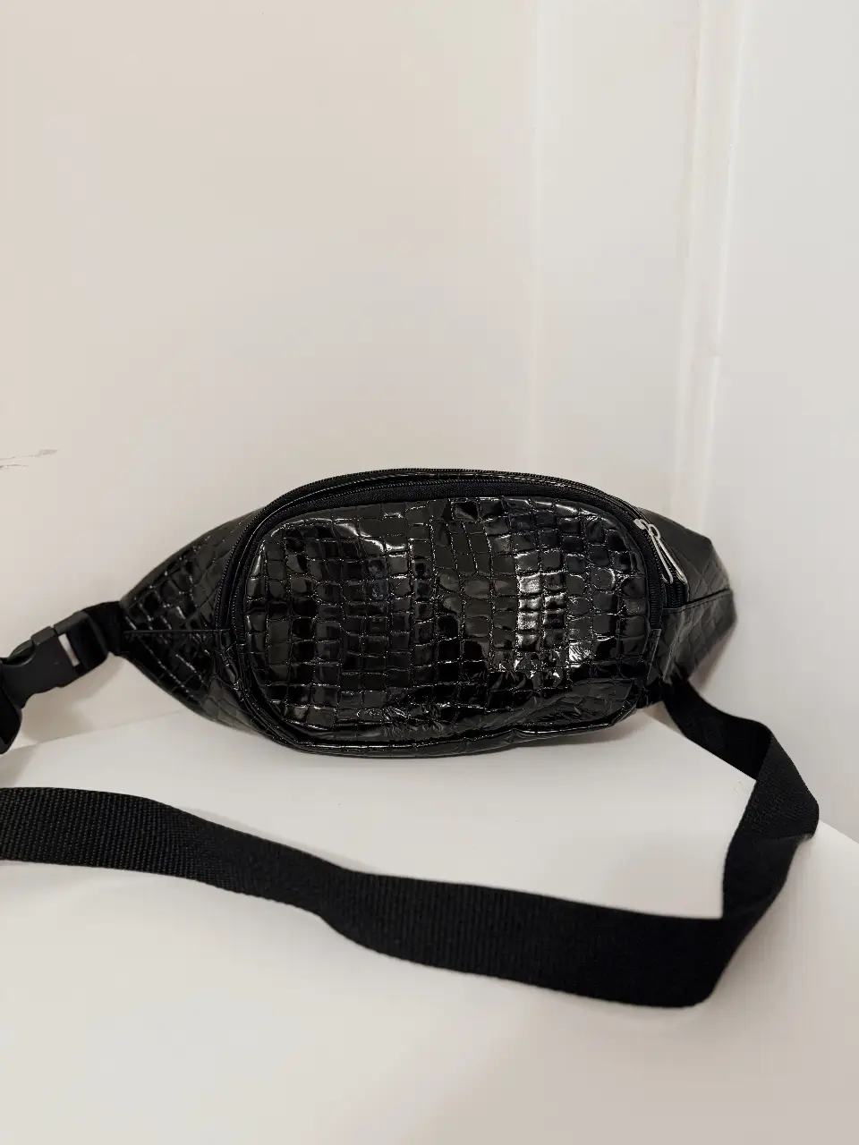 Riñonera negra con diseño símil piel de cocodrilo. Cuenta con cierre y correa ajustable. Ideal para llevar tus esenciales con estilo y comodidad. detalles de uso en foto