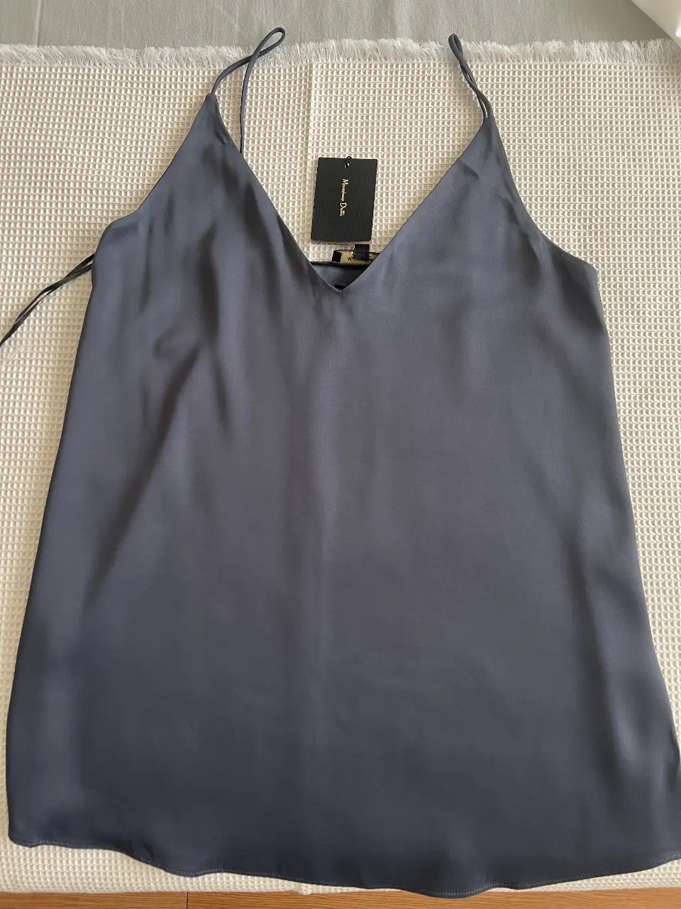 Top de seda gris oscuro con tirantes finos y escote en V. Ideal para combinar con pantalones de vestir o faldas para un look elegante y sofisticado.