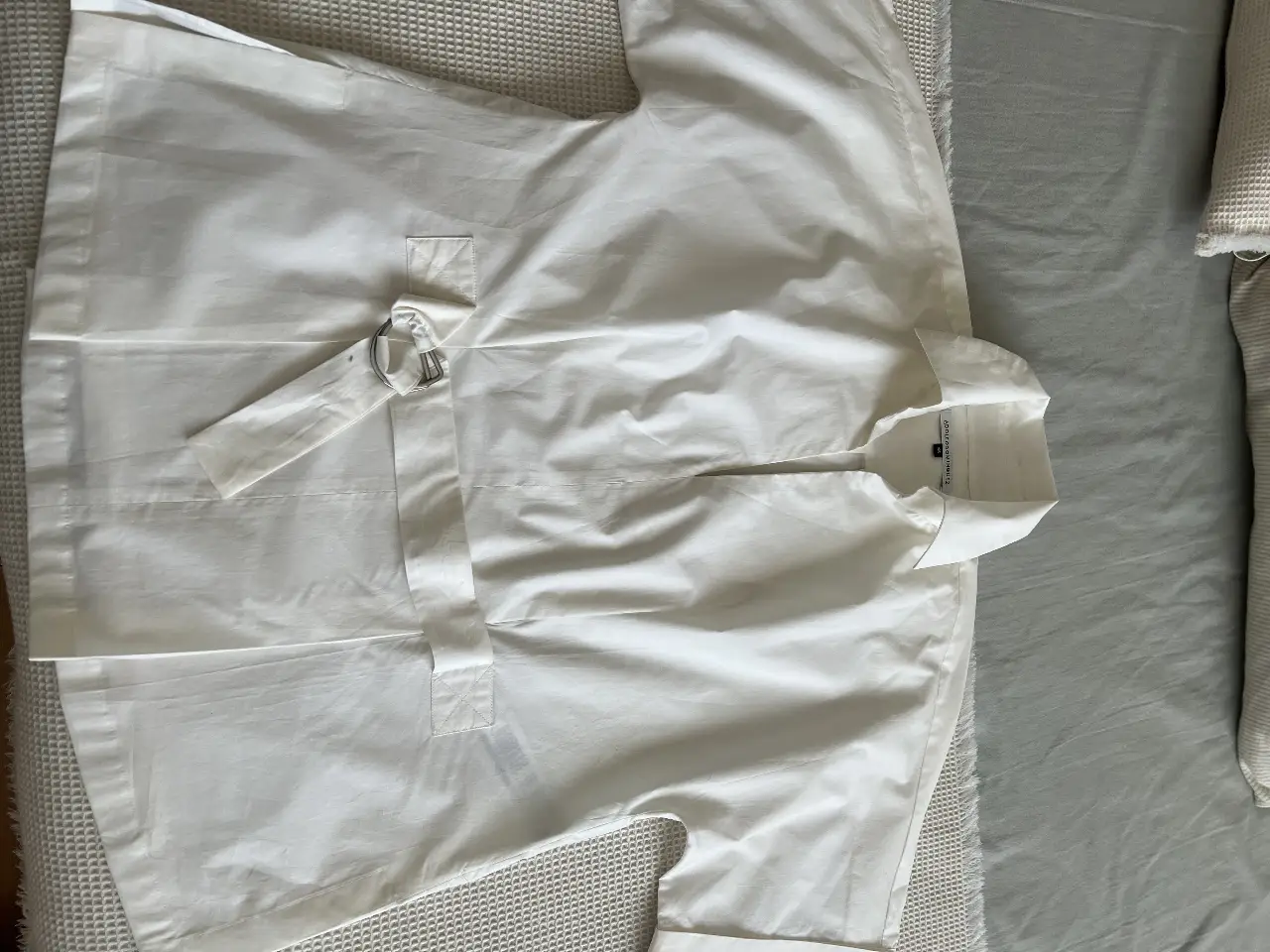 Camisa blanca con diseño moderno, con cinturón y hebilla. Ideal para un look elegante y sofisticado.