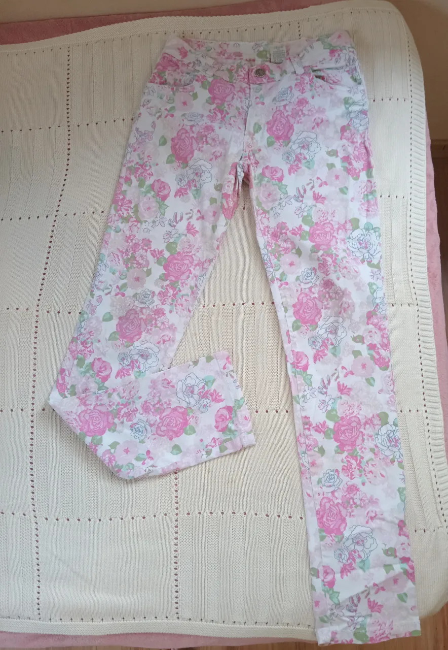 Pantalón de jean blanco con estampado floral. Posee bolsillos delanteros y traseros. Mide 89 cm de largo y 66 cm de cintura. Talle 14 angosto.