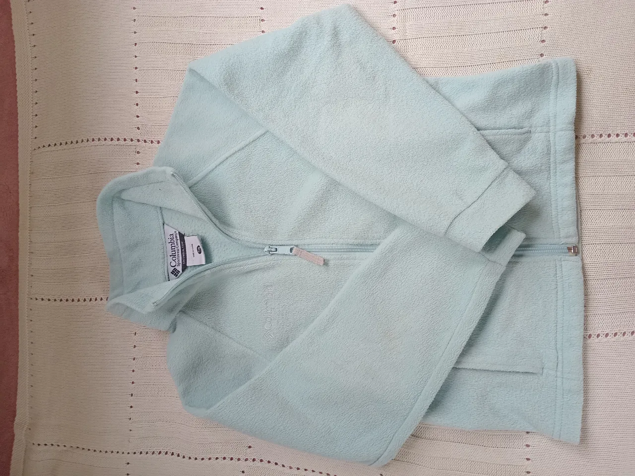 campera polar color celeste con cierre completo y cuello alto. Posee dos bolsillos frontales con cierre.