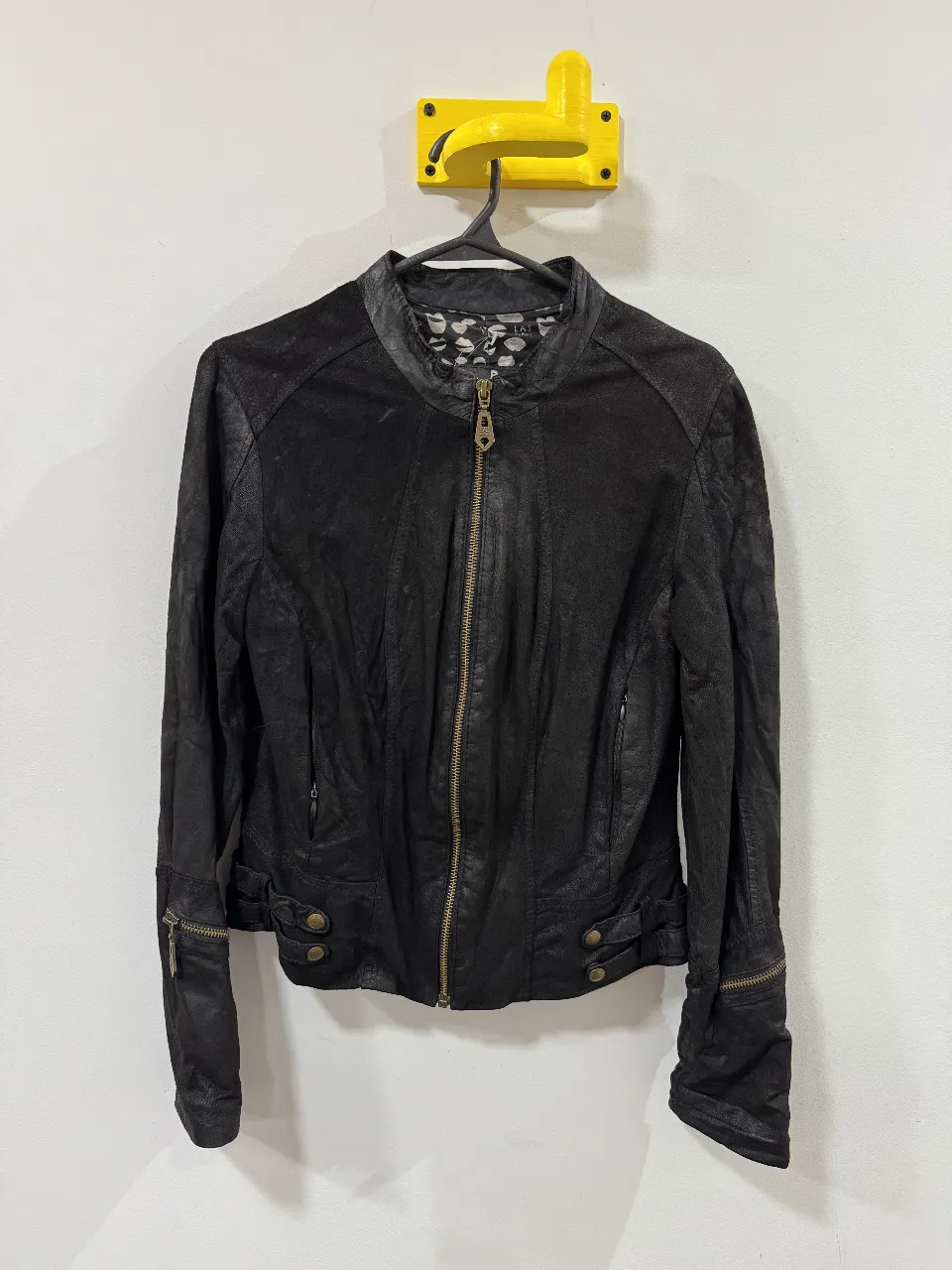 Campera biker de cuero negro para mujer, con cierre frontal y detalles dorados. Estilo rockero y elegante, ideal para salidas.